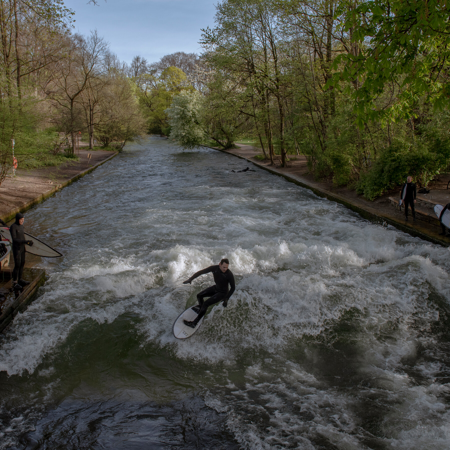 Peselancar menikmati gelombang Eisbach yang ikonik di Munich, sebelum lenyap secara misterius, memicu perdebatan restorasi.