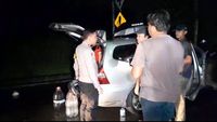 Anggota kepolisian sigap memberikan bantuan kepada pengendara yang mobilnya mogok di jalan sepi pada malam hari.