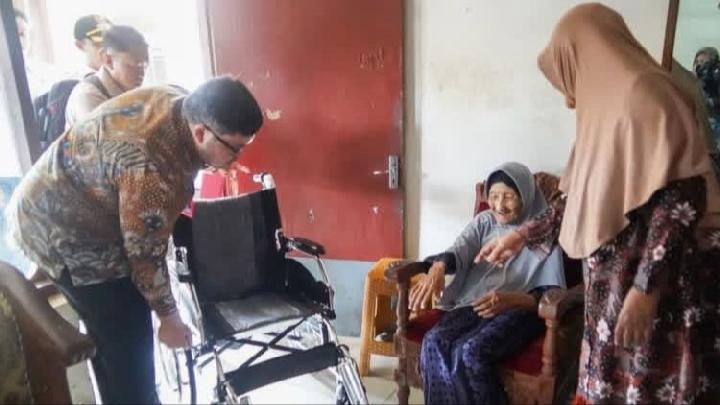 Bupati Kediri, Hanindhito Himawan Pramana, menyerahkan kursi roda kepada CJH tertua Mbah Marsiyah sebagai bentuk perhatian khusus kepada jemaah lansia di Kediri.