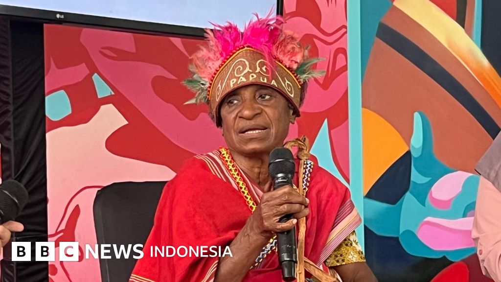 Seorang perempuan adat memegang hasil bumi di tengah hutan, simbol koneksi mendalam antara perempuan dan kelestarian lingkungan.