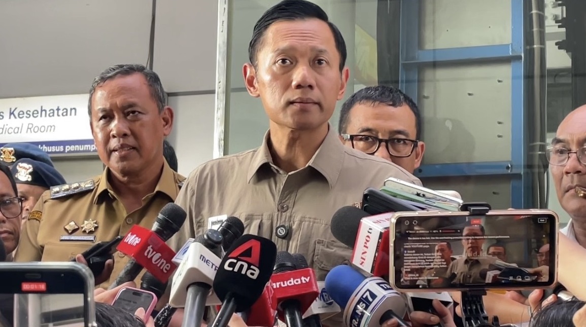 Seorang petugas berjaga di perlintasan kereta api sebidang yang dilengkapi palang pintu, mengingatkan urgensi keselamatan dan pengawasan di titik rawan kecelakaan.