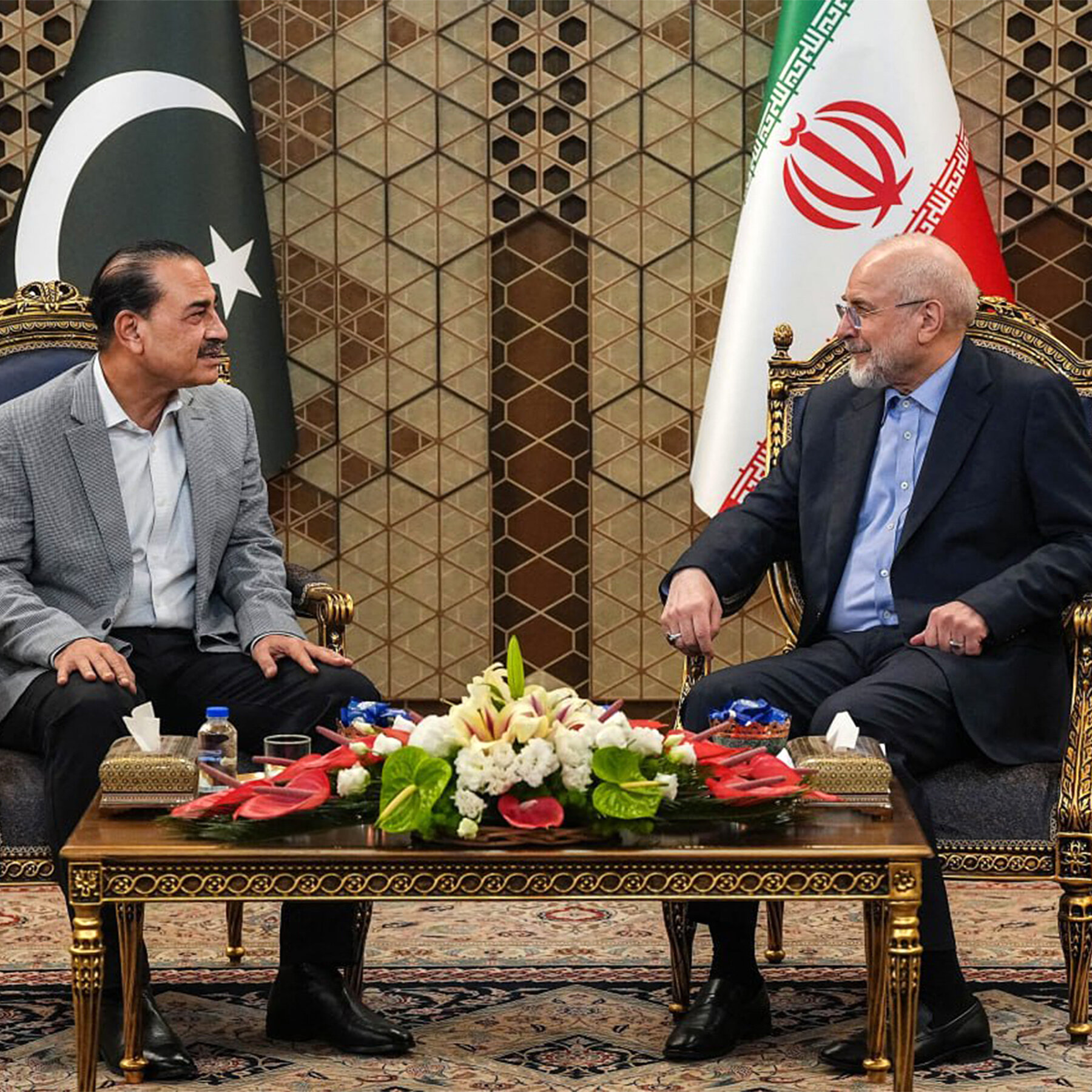 Bendera Amerika Serikat dan Iran berkibar di hadapan peta Timur Tengah, melambangkan diplomasi dan negosiasi yang sedang berlangsung untuk stabilitas regional.