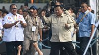 Driver ojek online menunggu pesanan di pinggir jalan, menghadapi perubahan regulasi potongan aplikator yang baru.
