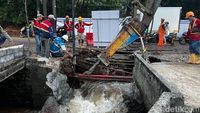 Petugas Sudin SDA Jakarta Selatan membongkar turap air di Jalan Raya Lenteng Agung untuk melancarkan aliran air, mempercepat penanganan jalan amblas yang masih dalam perbaikan.