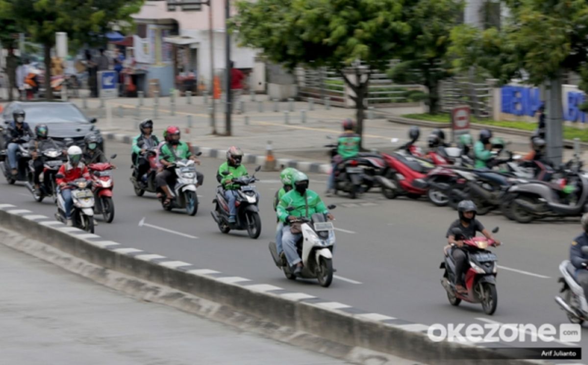 Pengemudi ojek online (ojol) beraktivitas di jalanan, menghadapi perubahan regulasi komisi yang signifikan.