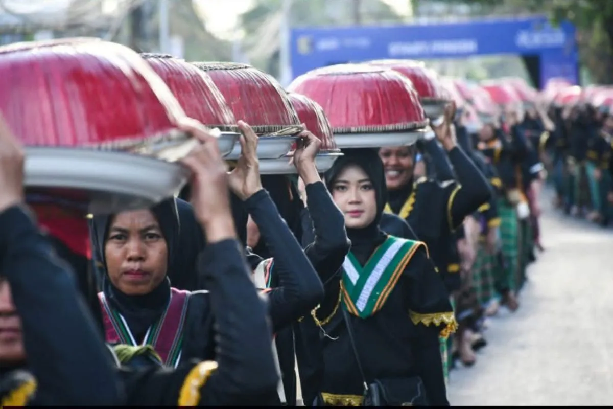Peserta mengarak dulang berisi makanan dalam perayaan Tahun Baru Hijriah di Lombok Timur, menampilkan kekayaan budaya dan kebersamaan.