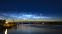 Kilauan keperakan awan noctilucent menghiasi langit saat senja di lintang tinggi, menandai dimulainya musim penampakan awan tertinggi di atmosfer Bumi.