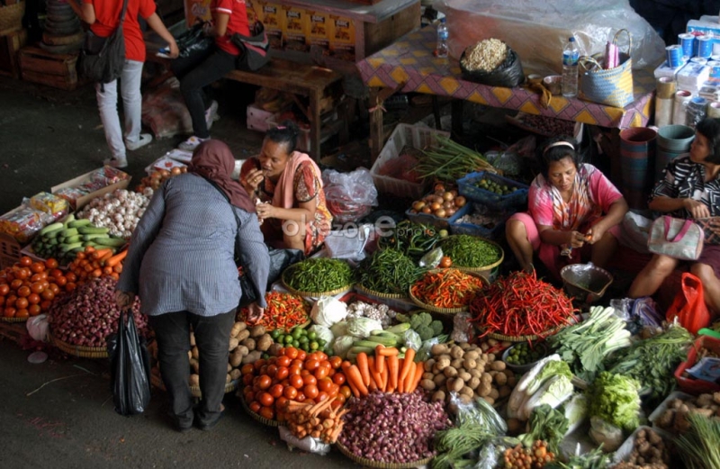 Aktivitas perdagangan di pasar tradisional, memperlihatkan tumpukan bawang merah dan cabai rawit yang harganya berfluktuasi.