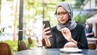 Ilustrasi jari memegang smartphone, menunjukkan aktivitas berkirim pesan yang kerap menyimpan isyarat emosional tak terucap dan potensi ketidaksukaan.