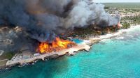 Asap hitam pekat mengepul dari atap jerami hotel yang terbakar di resor Pantai Bayahibe, Republik Dominika, pada Jumat (19/6), menarik perhatian global.