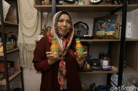 Nurhaeda, mantan terapis spa yang kini sukses sebagai pengusaha jamu rempah, menunjukkan produk-produknya. Dukungan Rumah BUMN BRI melalui pelatihan digital marketing menjadi kunci transformasinya dalam memperluas jangkauan pasar.