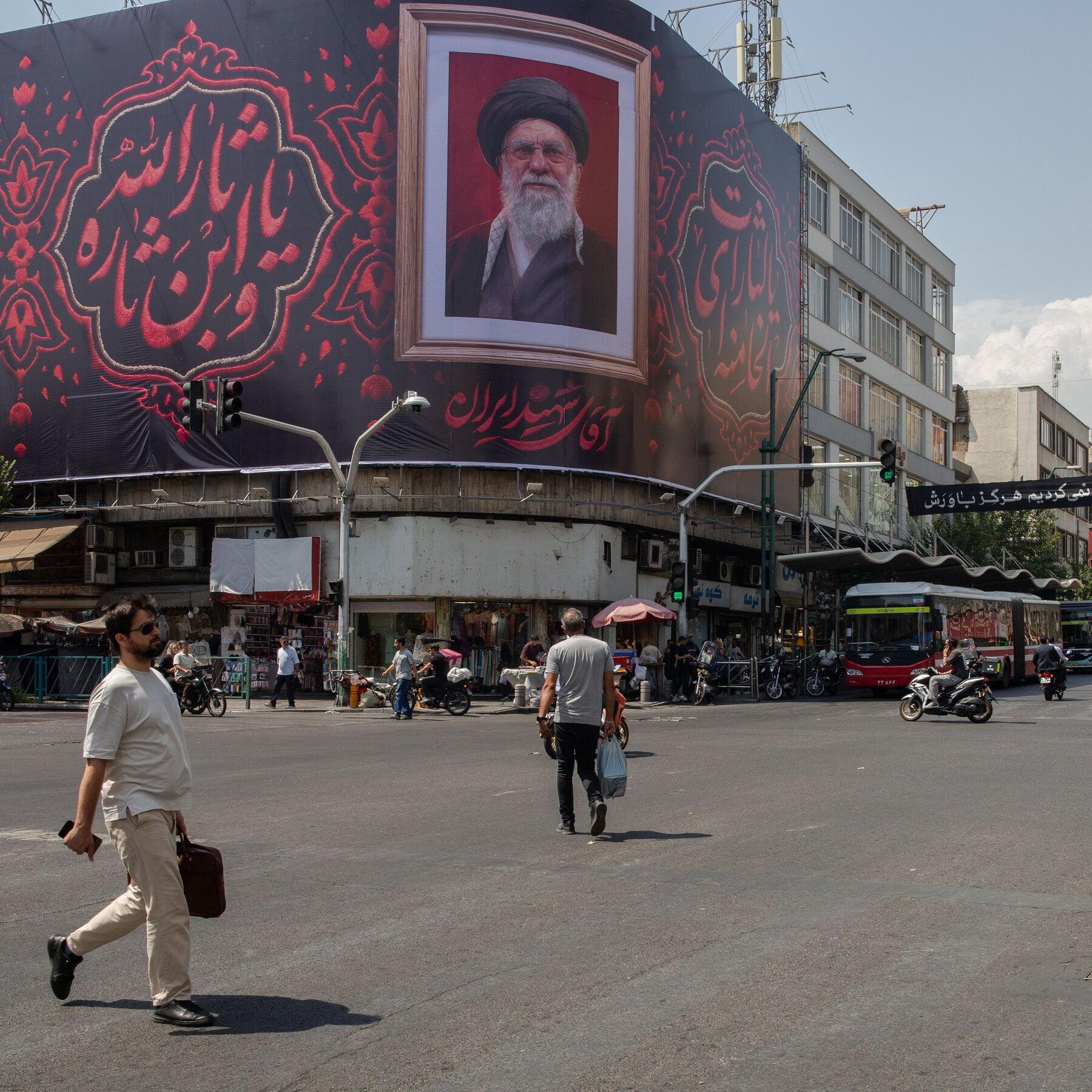 Seorang warga Iran berduka di hadapan poster Pemimpin Tertinggi Ayatollah Ali Khamenei. Pemakaman massal akan menjadi momen krusial bagi rezim Iran untuk menunjukkan ketahanan di tengah gejolak.