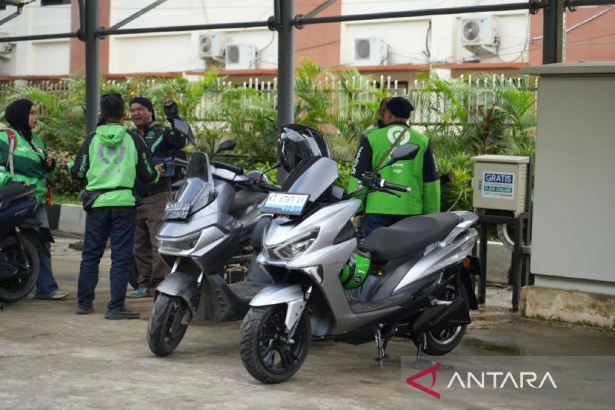 Pengemudi ojek online memanfaatkan fasilitas pengisian daya motor listrik gratis, sebuah inisiatif Pemerintah Provinsi Kalimantan Timur untuk mendukung mobilitas hijau dan efisiensi energi.