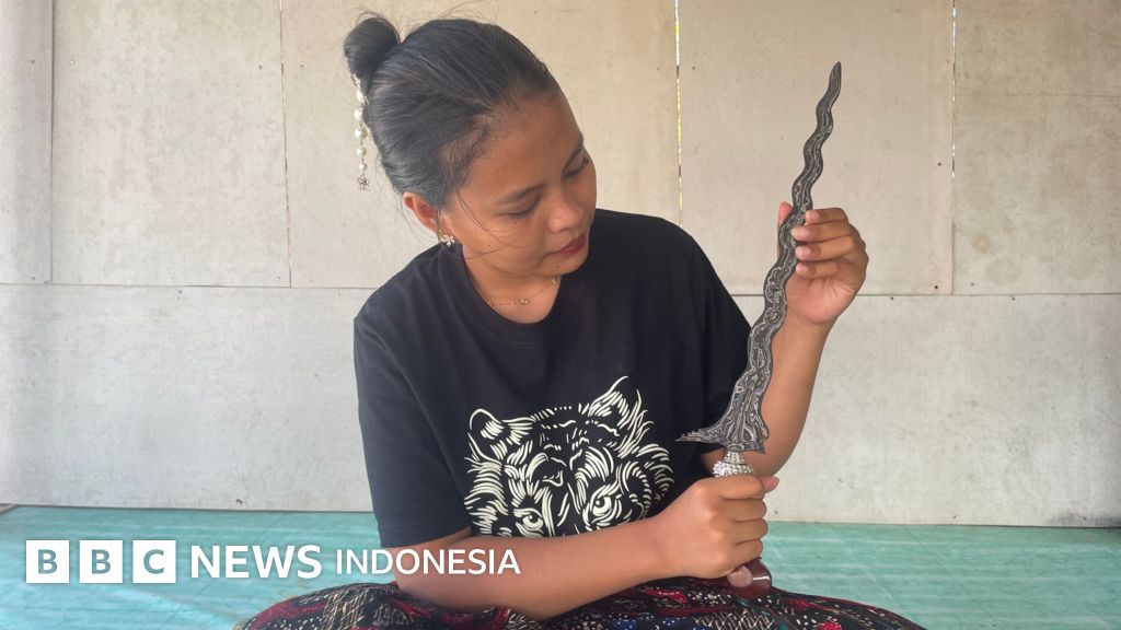 Sisil, empu keris perempuan asal Sumenep, Madura, menunjukkan bilah keris yang ia tempa, melambangkan perjuangan dan dedikasinya dalam melestarikan warisan budaya.