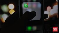 Ilustrasi seseorang sedang memeriksa ponsel dengan ekspresi waspada, menggarisbawahi pentingnya kewaspadaan terhadap ancaman siber pada aplikasi pesan seperti WhatsApp.