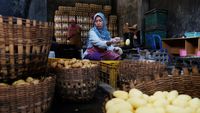 Seorang pelaku UMKM sedang menata produk kerajinan tangannya, mencerminkan semangat kewirausahaan lokal yang terus berinovasi di tengah tantangan ekonomi.
