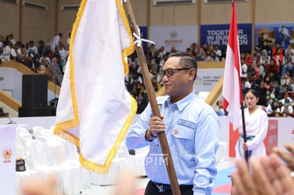 Potret Wakil Gubernur Kalimantan Timur, Seno Aji, saat memegang bendera organisasi dalam sebuah acara olahraga.