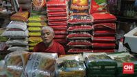 Tumpukan karung beras di gudang distributor yang kontras dengan rak kosong di toko modern, menggambarkan ironi kelangkaan beras premium di pasar.