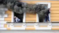 Warga Ukraina bergegas menyelamatkan diri dari puing-puing gedung Akademi Ilmu Pengetahuan setelah serangan drone Rusia melanda pusat pada Senin, 28 September.