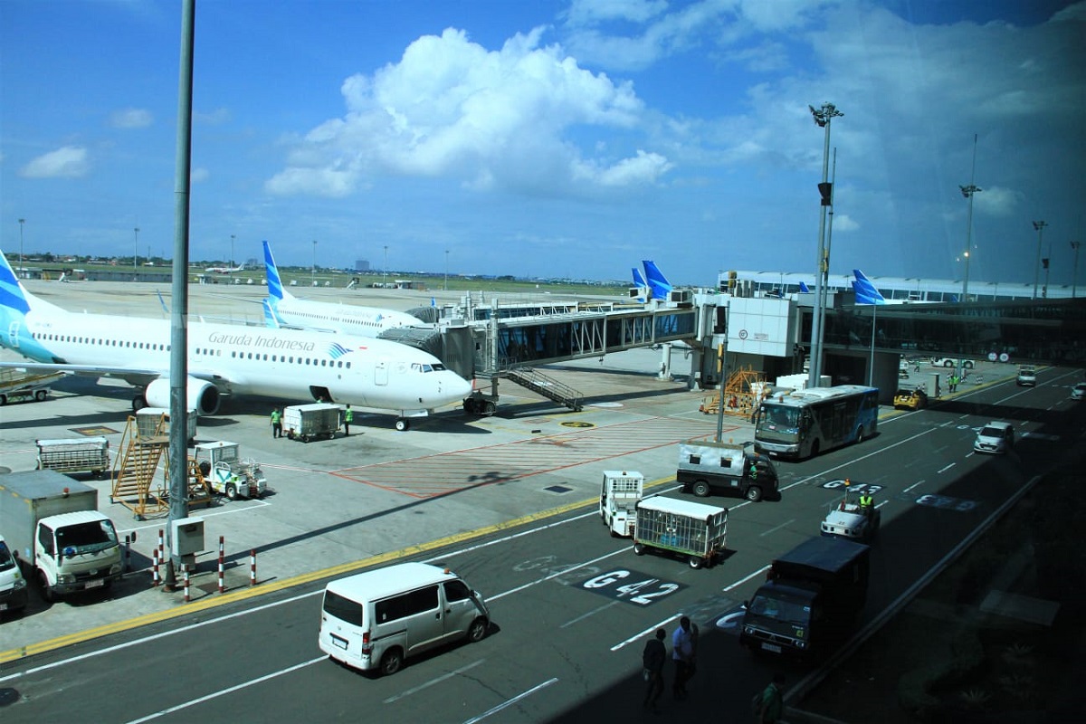 Pesawat Garuda Indonesia sedang mendarat di landasan pacu, simbol kembalinya layanan penerbangan yang vital.
