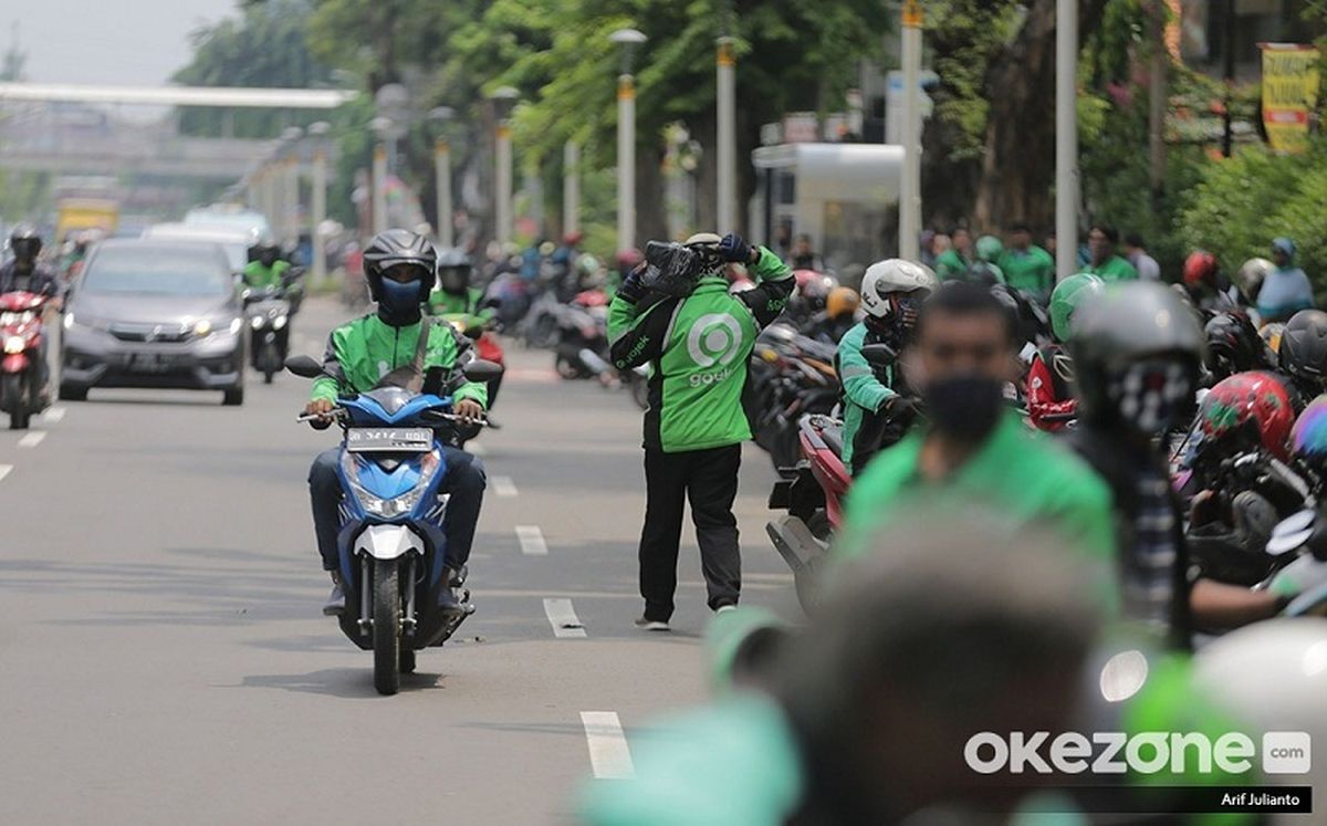 Ilustrasi pengemudi ojek online di jalan raya, menyoroti kebutuhan regulasi yang lebih jelas dari pemerintah terkait tanggung jawab aplikator dan mitra.